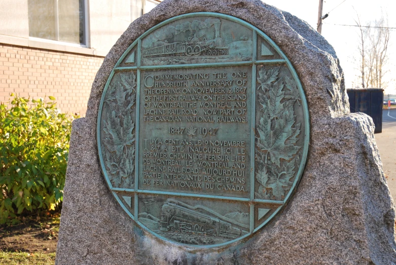 a plaque is on a stone outside on a street