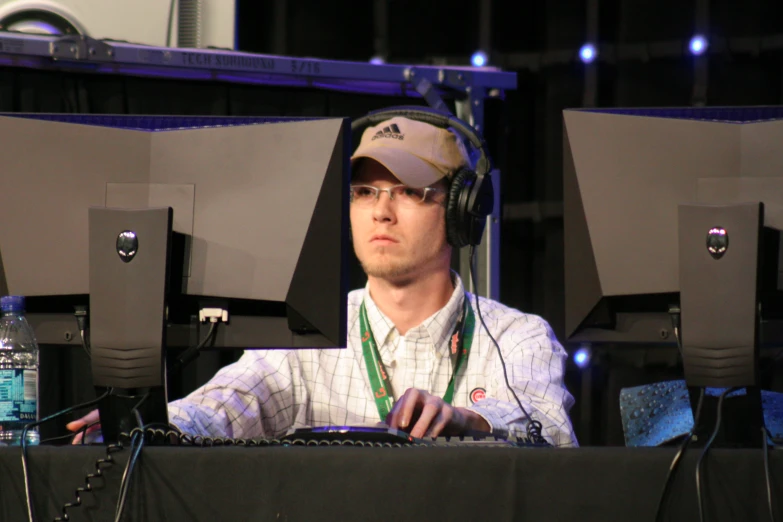 a man wearing headphones and standing behind some keyboards
