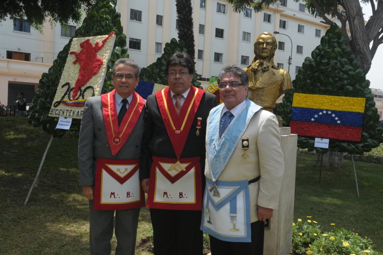 three men dressed in different colors stand by a statue