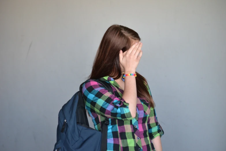 a woman is standing in front of a wall covering her face