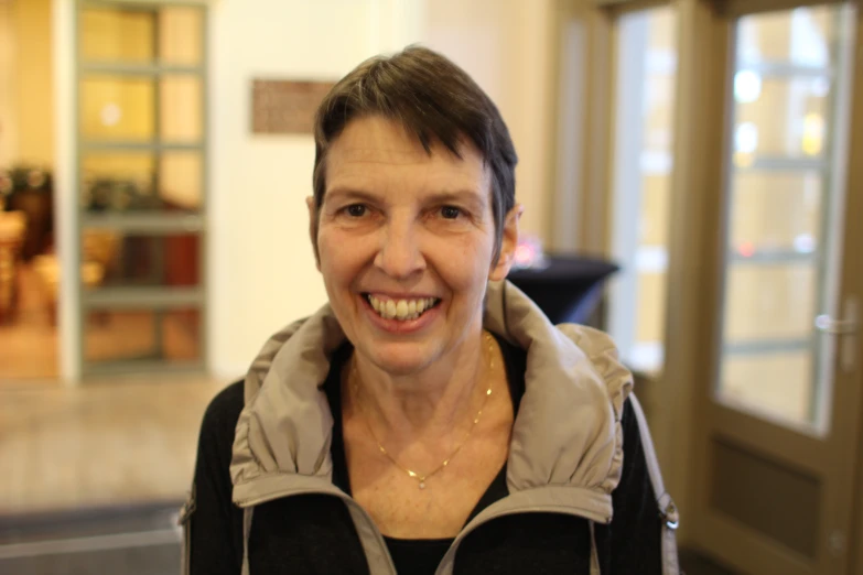 a woman smiling wearing a black jacket and a grey hoodie