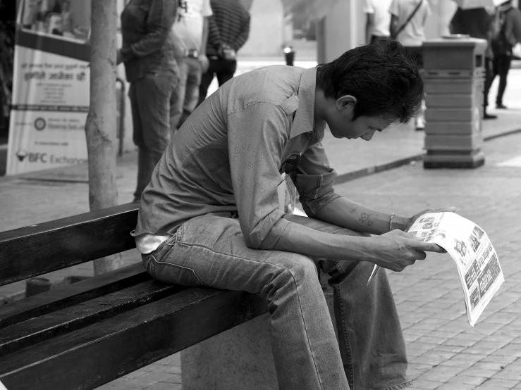 a man sitting on a bench reading a newspaper