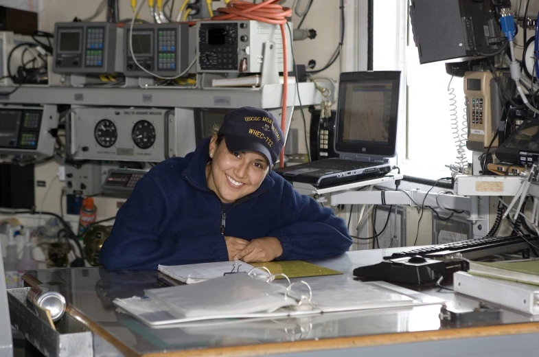 a smiling man at a table with computers in the background