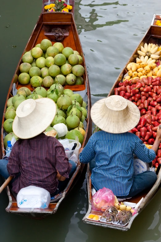 a couple of people in boats filled with lots of fruit