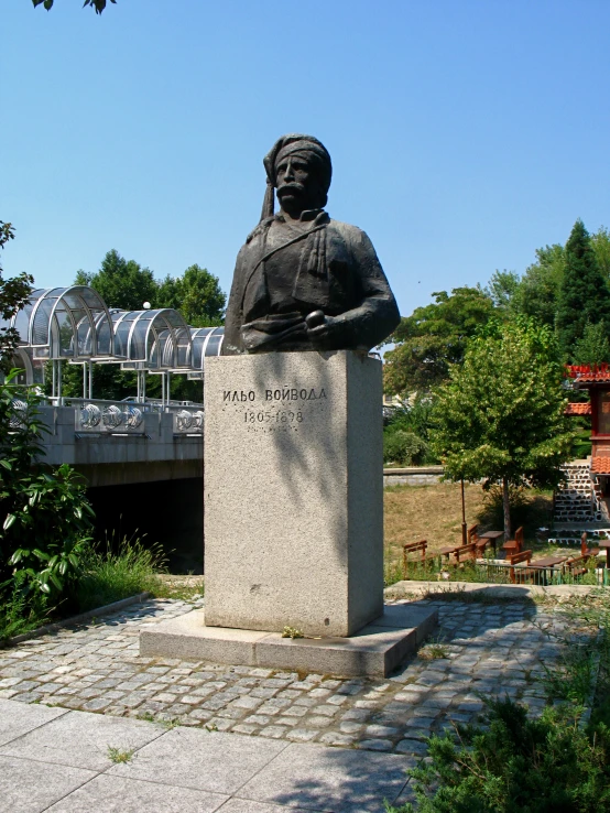 a big statue of a man by a bridge