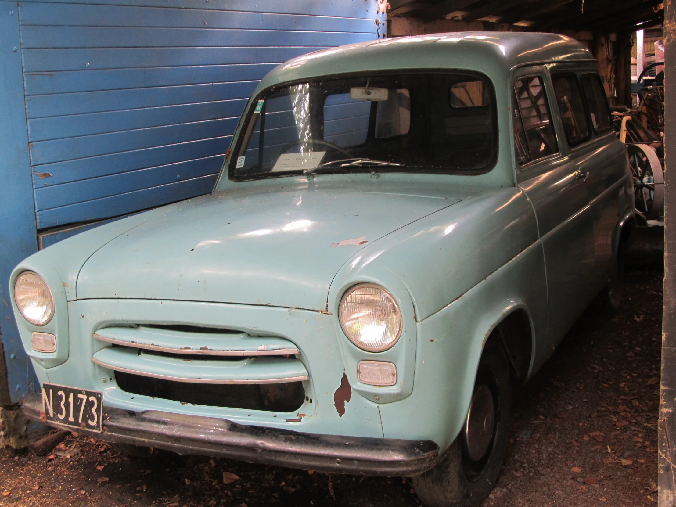 an old fashioned van with a blue garage behind it