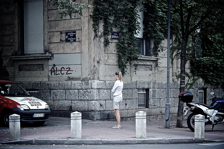 a person standing on the side of the street in front of a car and some parked cars