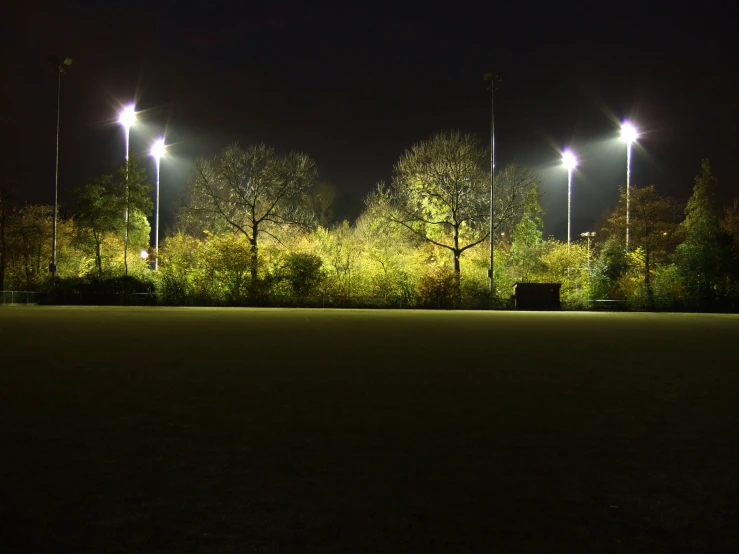 a empty park bench under street lights at night