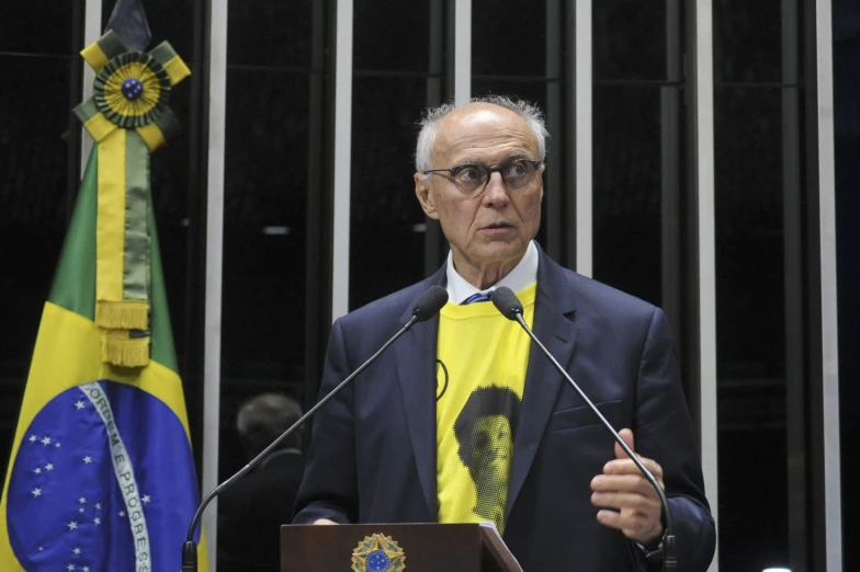 an old man stands behind a podium with flags