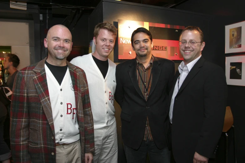 three men pose for the camera in front of a wall