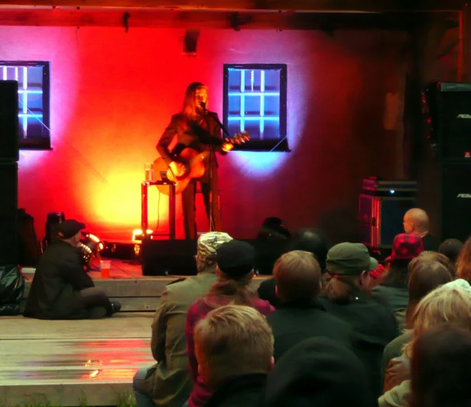 people watching a man talk on stage with a red light in the background