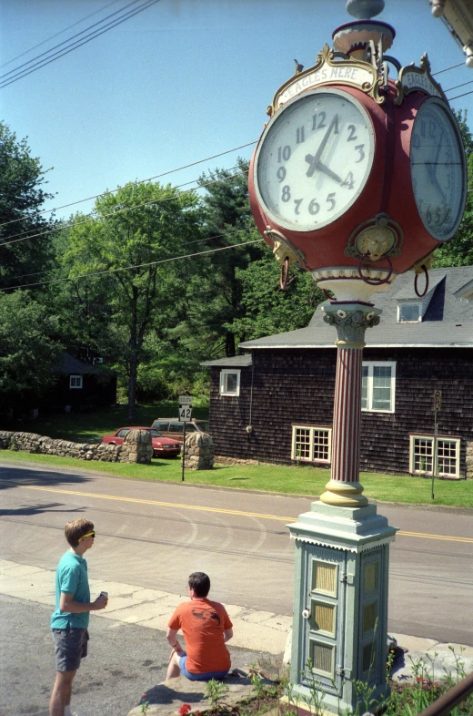 two children play near a clock on the sidewalk