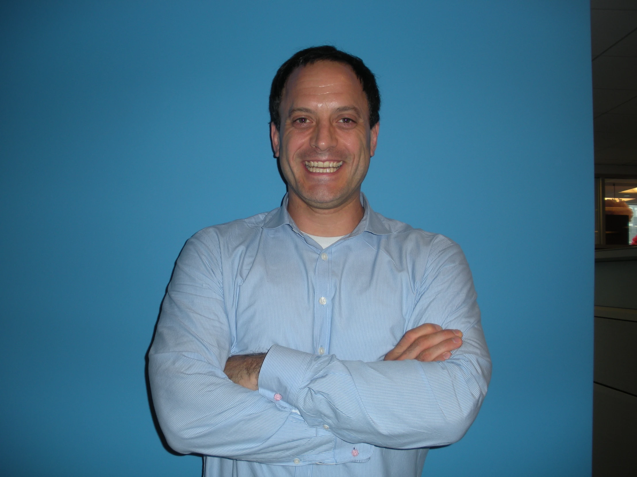 a man wearing a light blue shirt standing in front of a wall