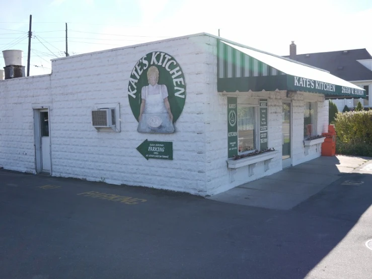 an old white brick building with a giant green woman on the front