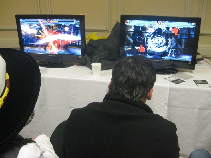 two people sitting at a table while playing video games