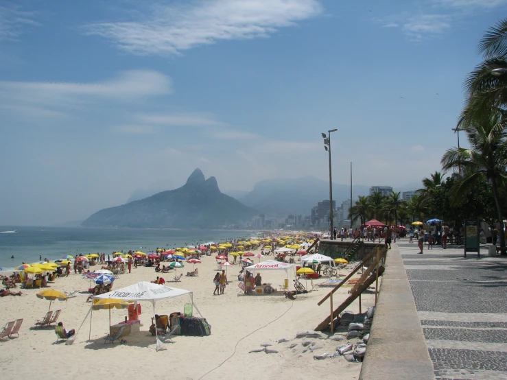 a sandy beach with many people walking around it