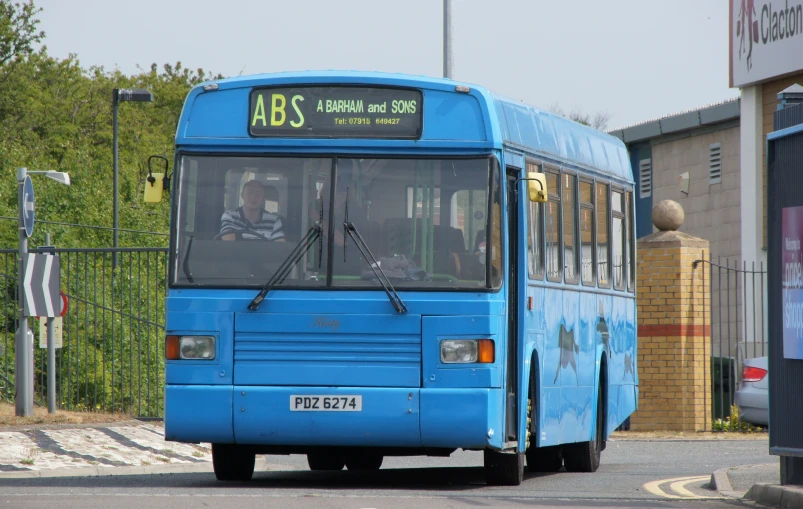 a blue bus on street next to building