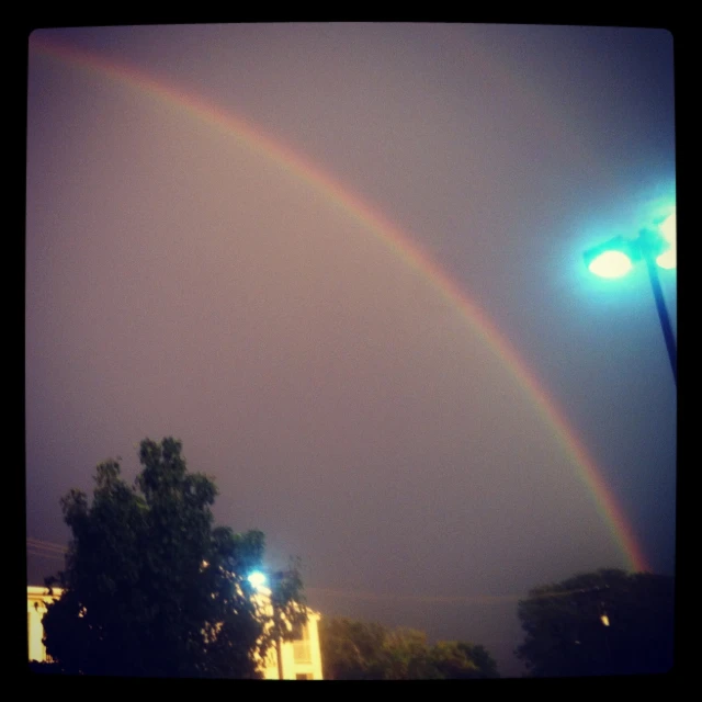 a rainbow appears over a city skyline as it begins to break