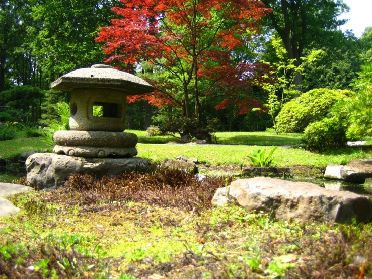 small rock sculpture in a japanese garden with a large tree