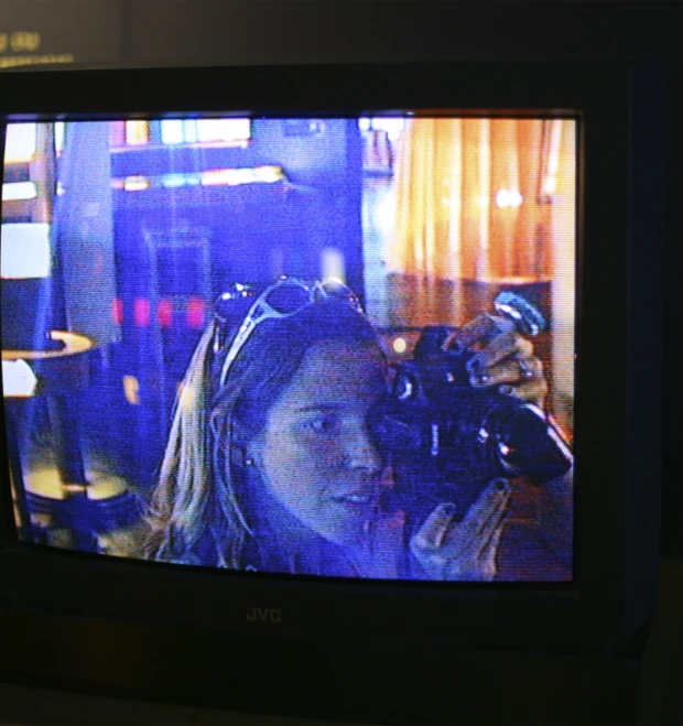 a woman is taking pictures while standing behind a tv