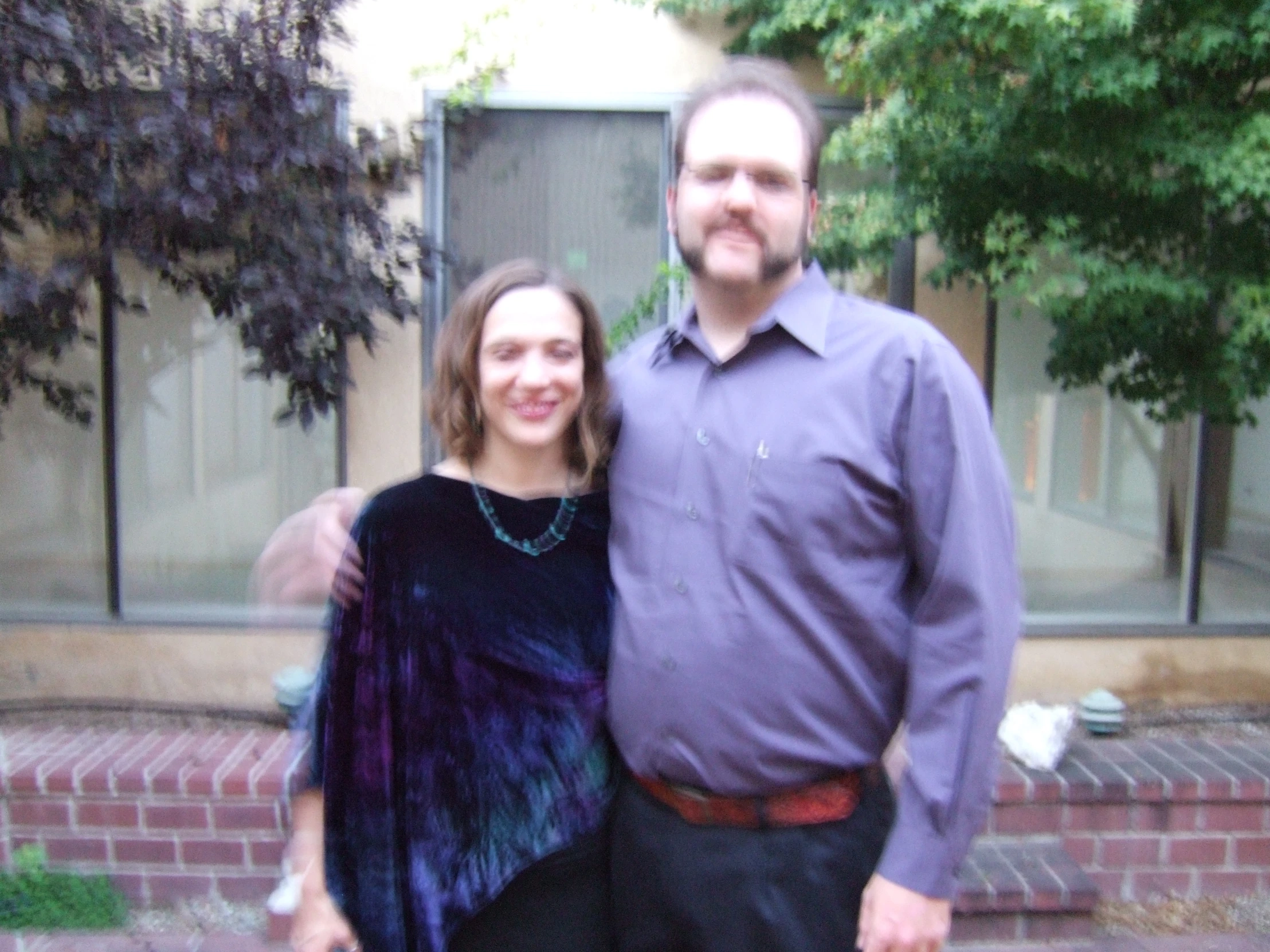 a man and a woman standing in front of a brick wall