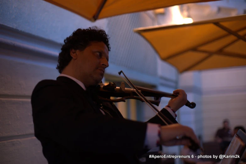 a man in a suit playing the violin under an umbrella