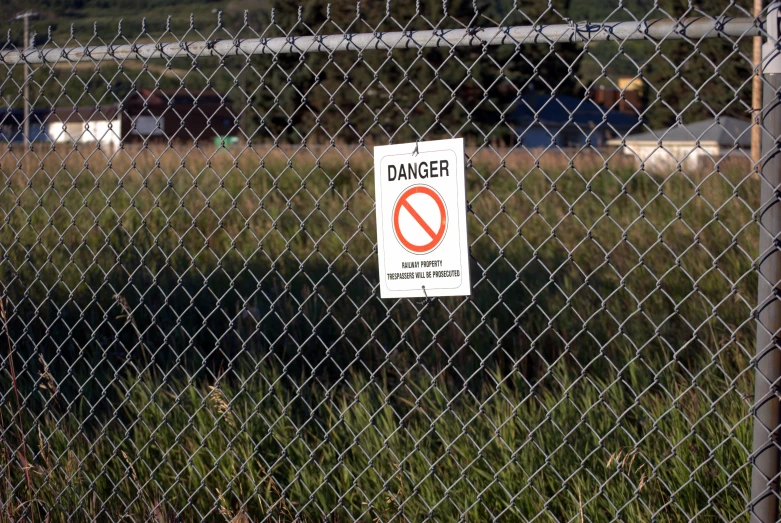 an industrial area has a fence that has a no smoking sign on it
