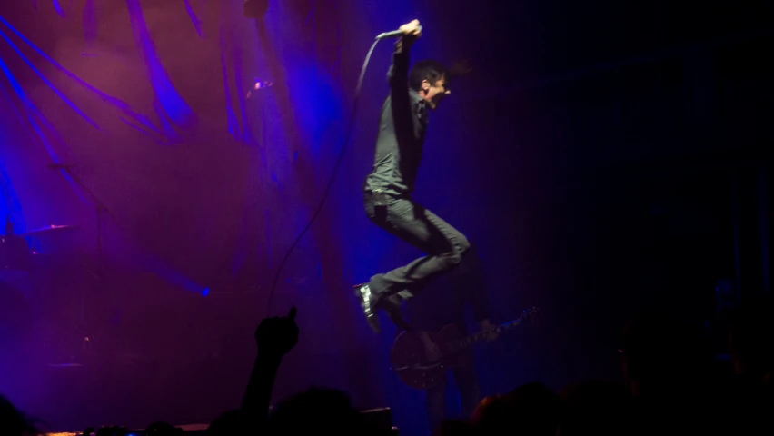 a man hanging upside down on a pole on stage