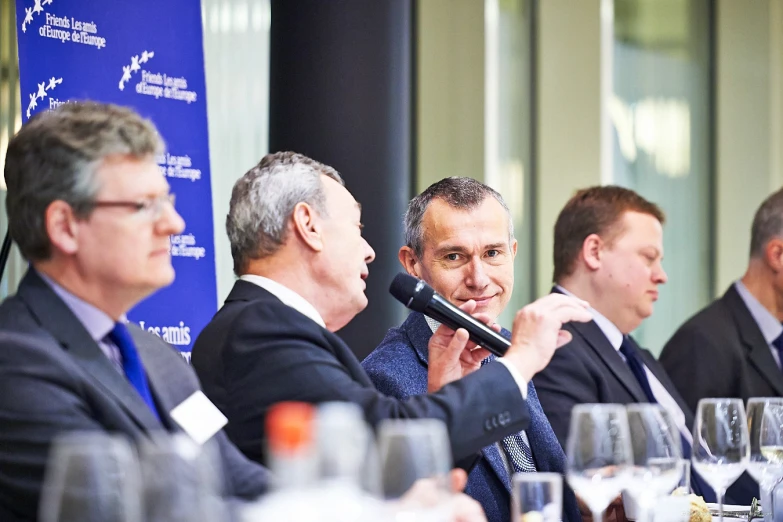 men sitting at tables and talking on microphones