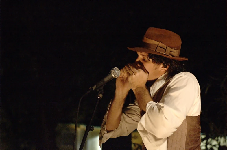 a man in a hat is singing into a microphone
