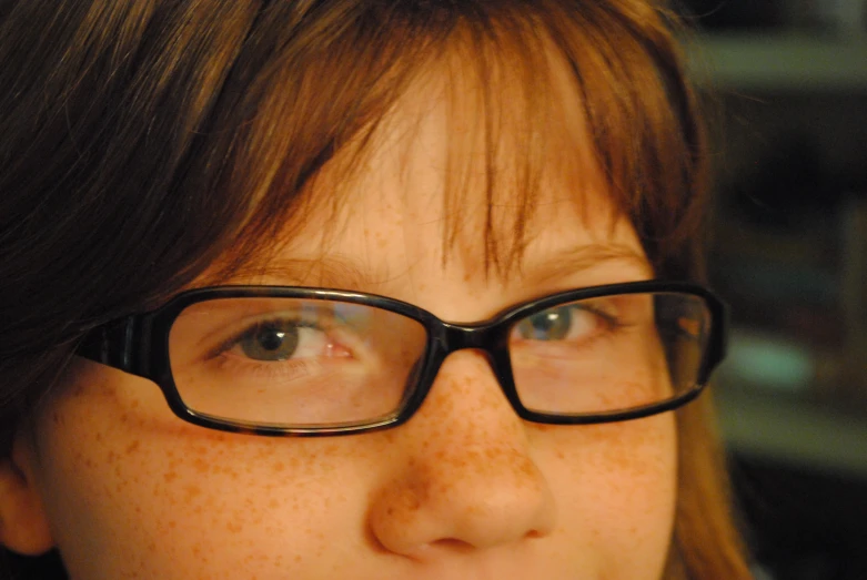 a girl with brown hair wearing black glasses