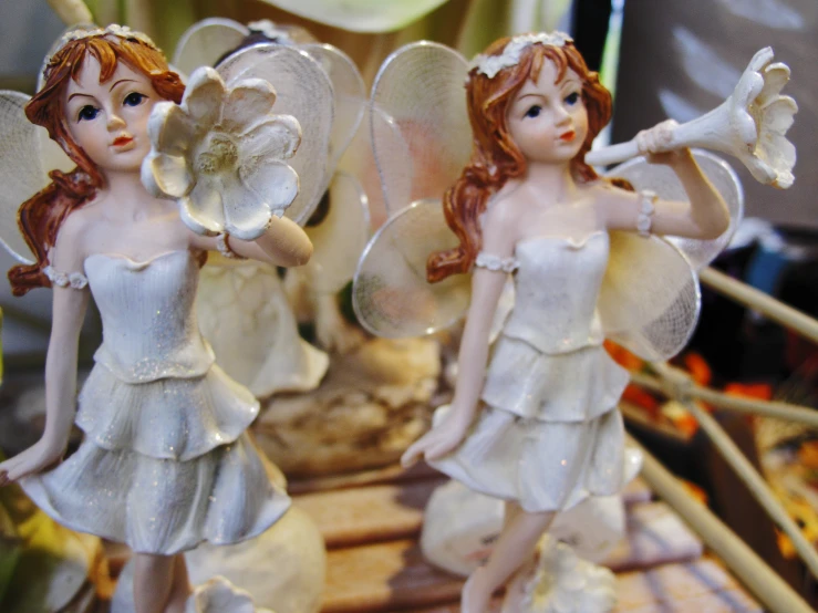 there are two ceramic angels holding flowers