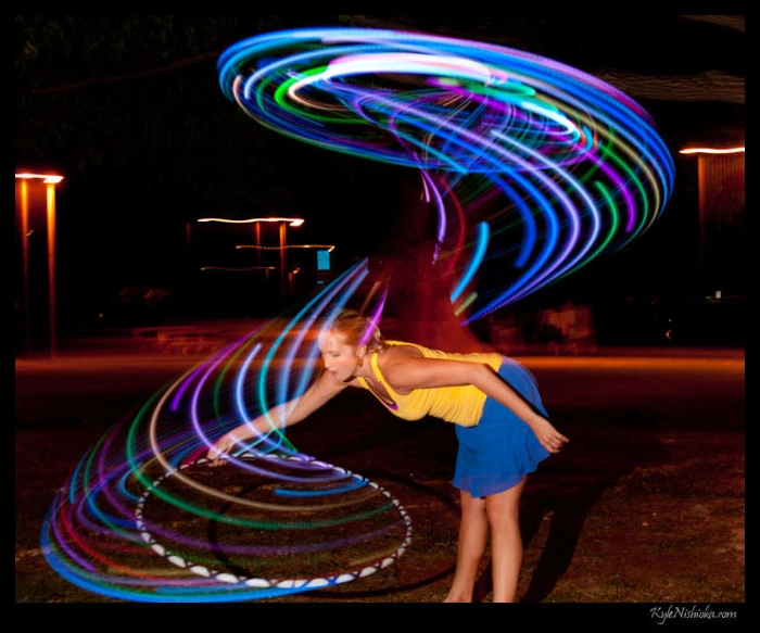 woman with dark background standing in a circle of multicolored lights