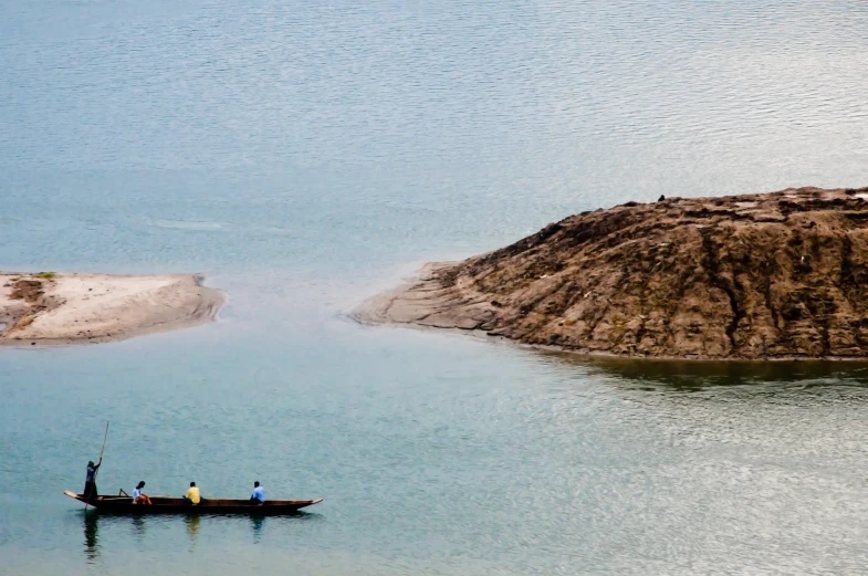 a man rows a long rowboat toward the shore