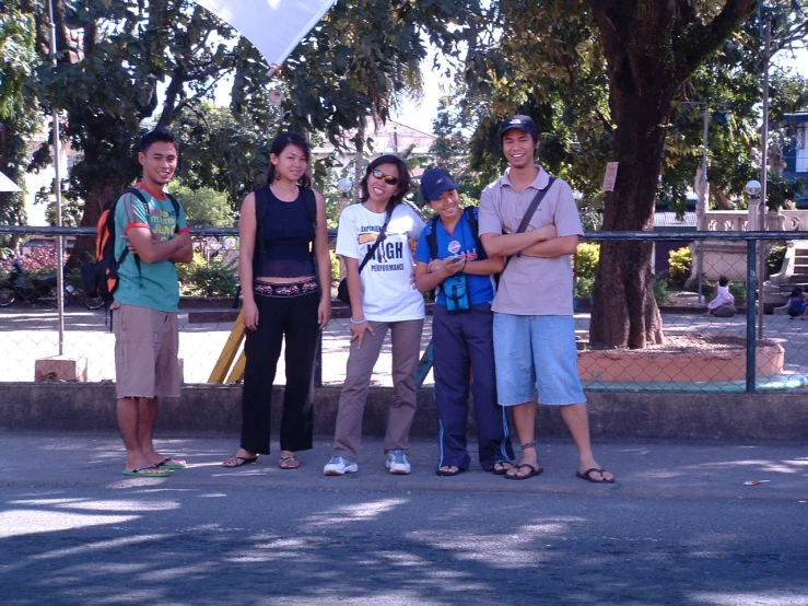 four people are posing for a picture in front of a fence