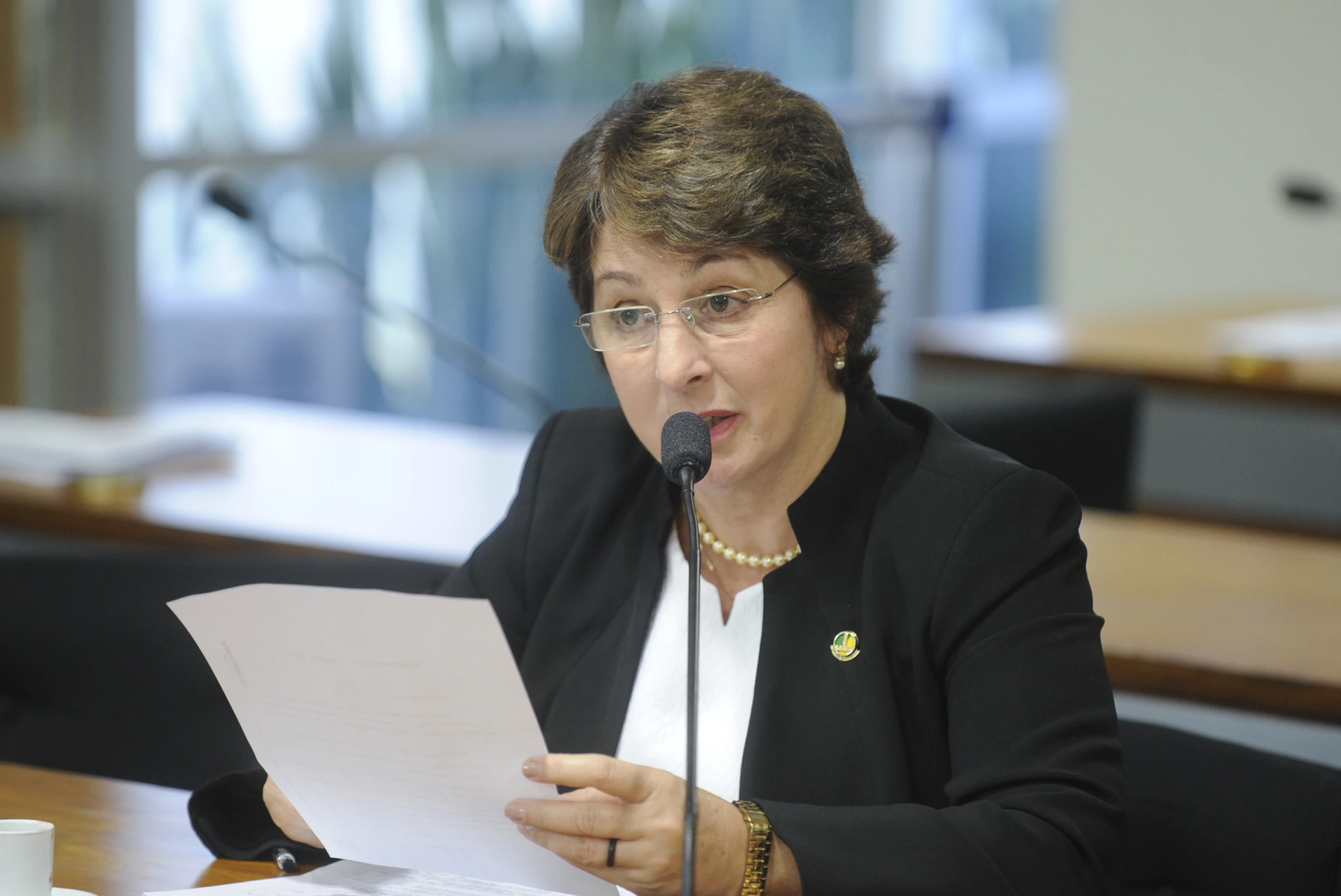 a woman reading a paper while standing in front of a microphone