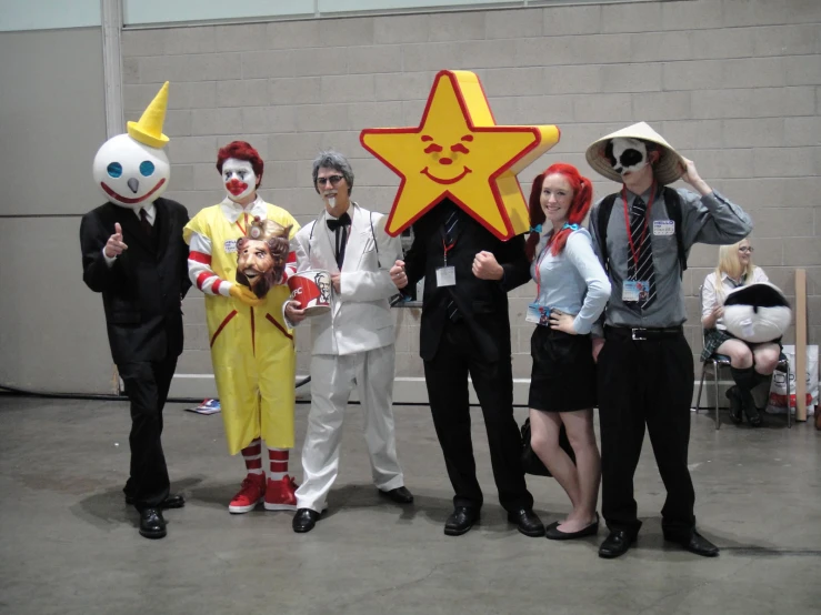 five people standing with masks of clowns and one person wearing a hat