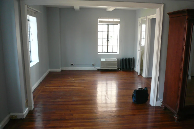 an empty room with hard wood floors, white walls and a radiator
