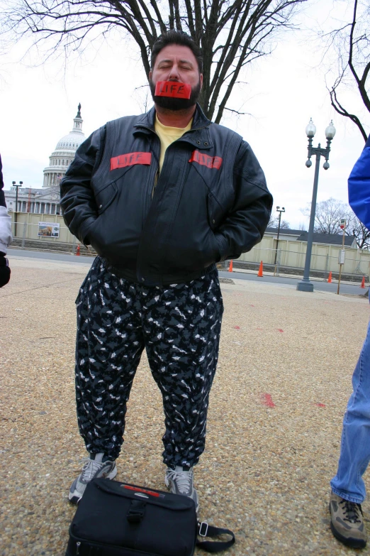 man in all black with red nose standing on suitcase