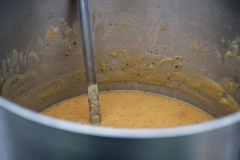 two metal whisks in a saucepan with mustard