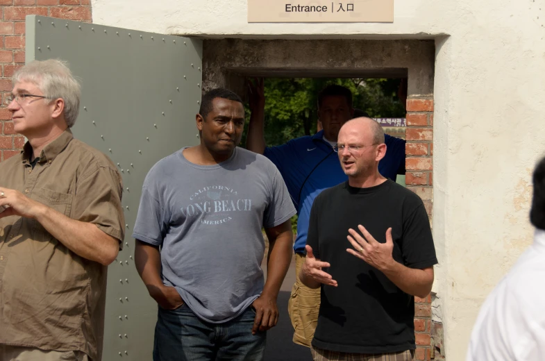 three men with black hair are outside of a building