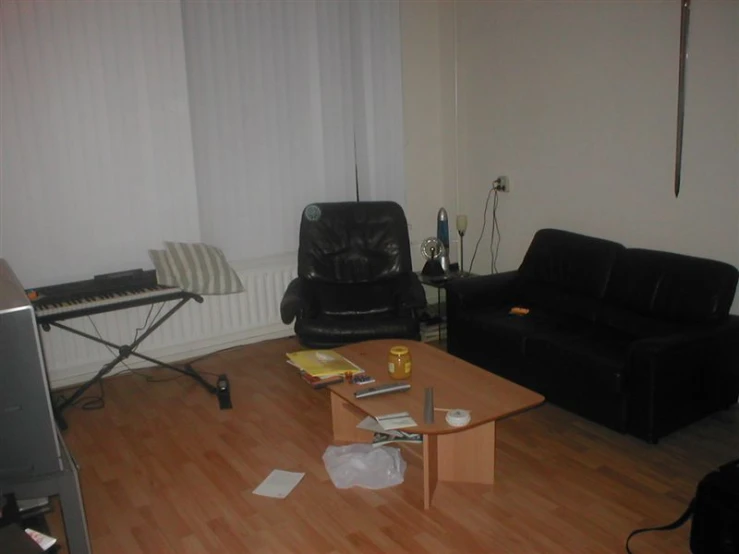 a room with a television, black couch, and piano