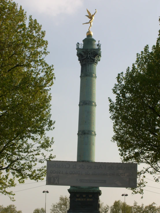 a monument has a statue on top that is in the middle of a park