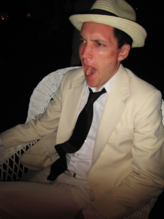 a man in a white suit and tie sticking his tongue out