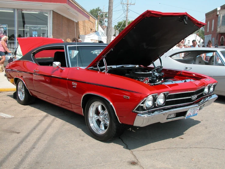 old car with a hood popped open in front of other cars