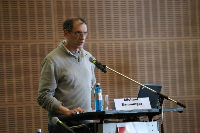 a man speaking into a microphone with writing on a piece of paper