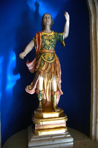 a statue of the god of love standing against a blue wall