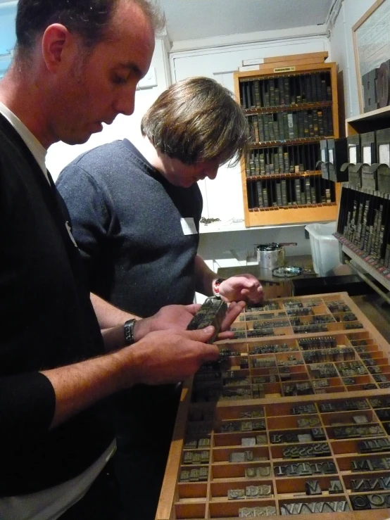 a man and woman standing next to each other looking at pictures