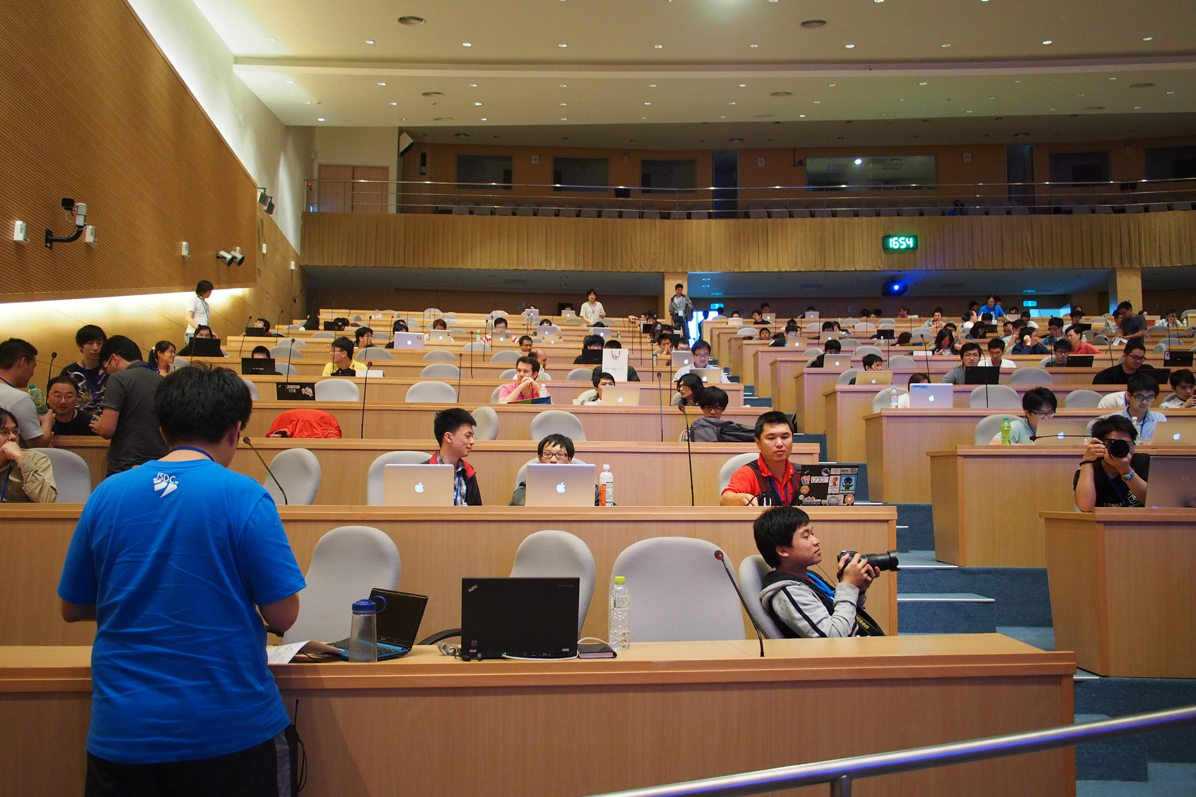 an auditorium filled with rows of desks and people on laptop computers