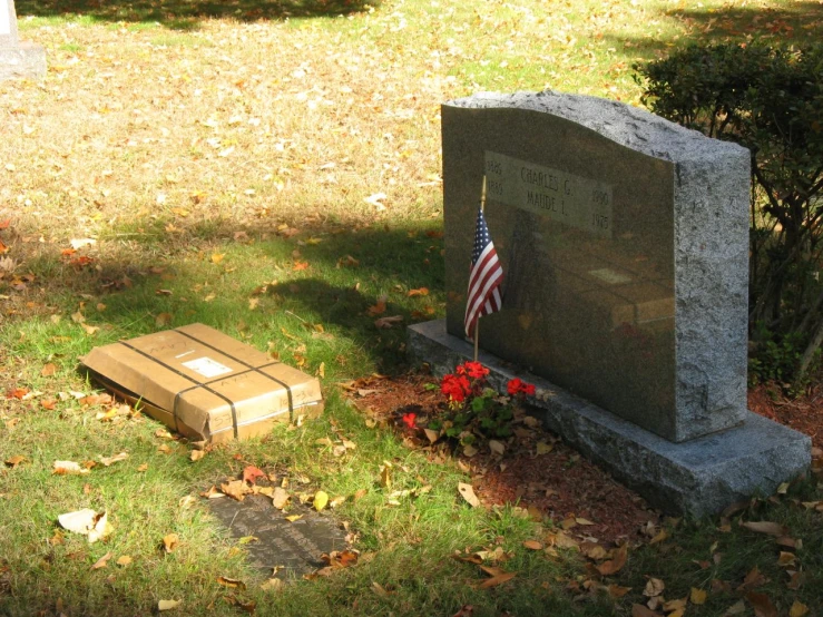 a stone grave in a grass field with american flag